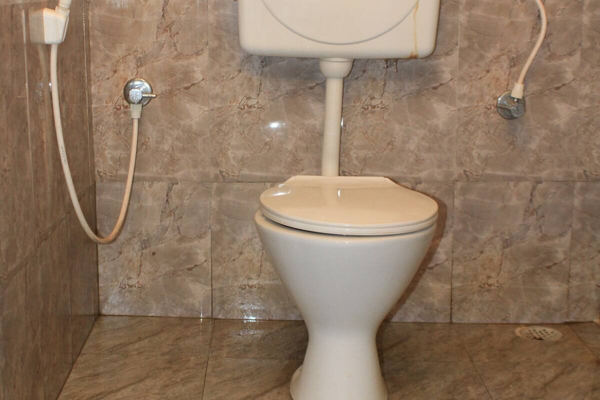 A toilet with a bidet attachment in a bathroom with marble flooring and walls.