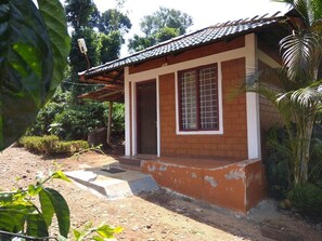 A single-story building with a tiled roof, a front porch, and a small garden area.