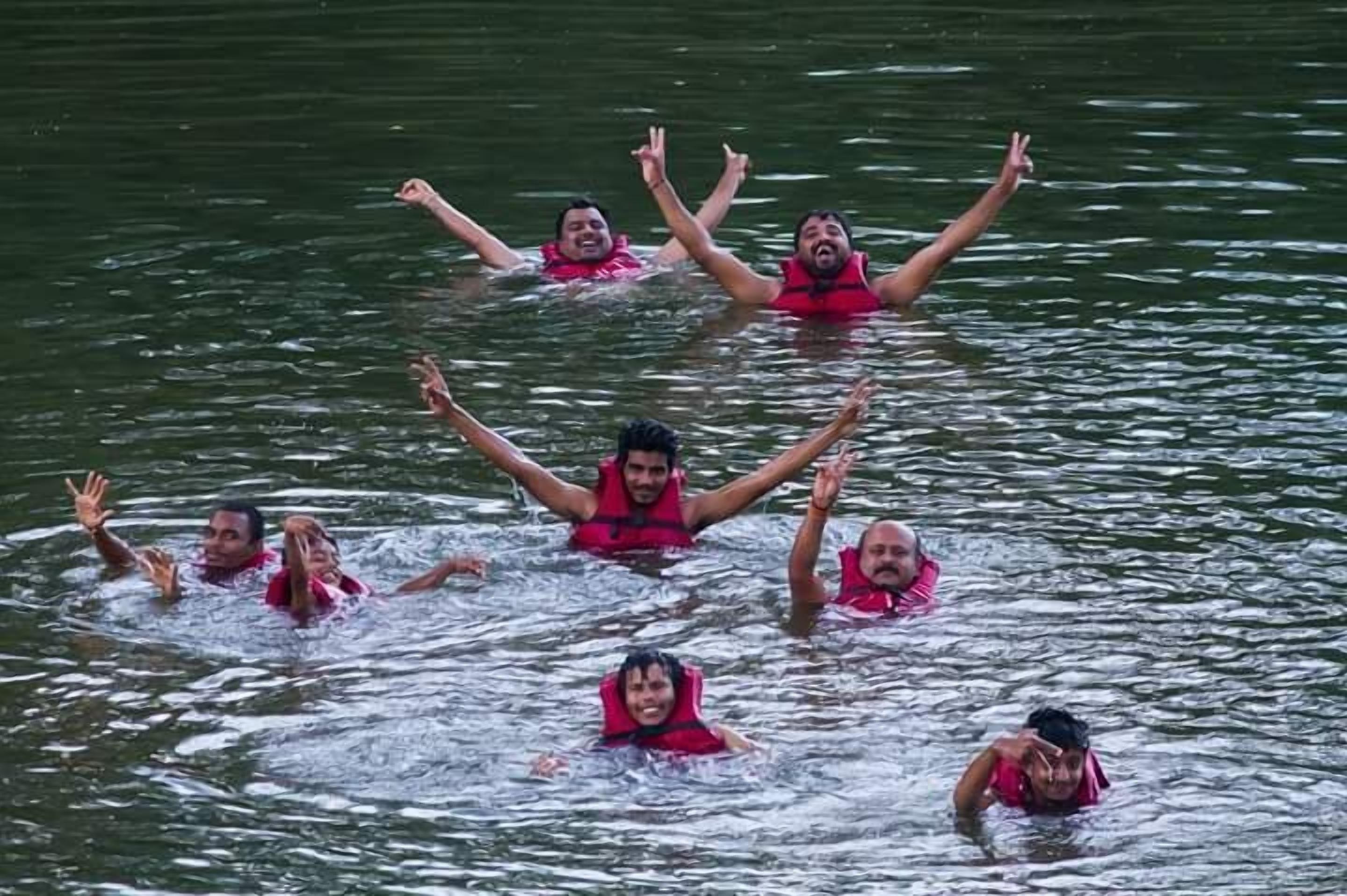 Un grupo de personas en el agua, con chalecos salvavidas rojos.