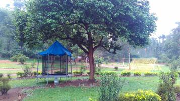 Un parco con un gazebo blu, un albero grande e un pallone da calcio.