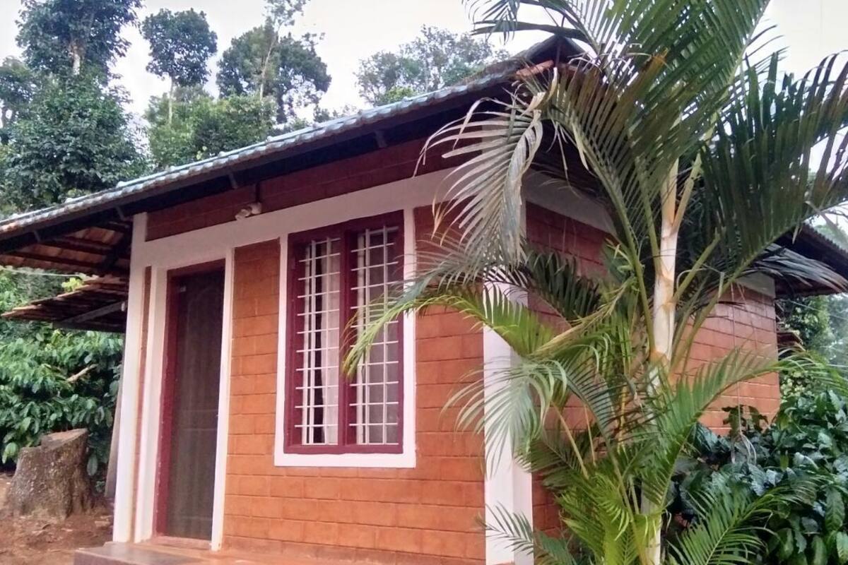 A small, single-story building with a sloped roof, a wooden door, and a window with bars.