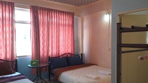 A bedroom with two beds, a small table, and a bunk bed. - OK Home Hostel (Bangkok)