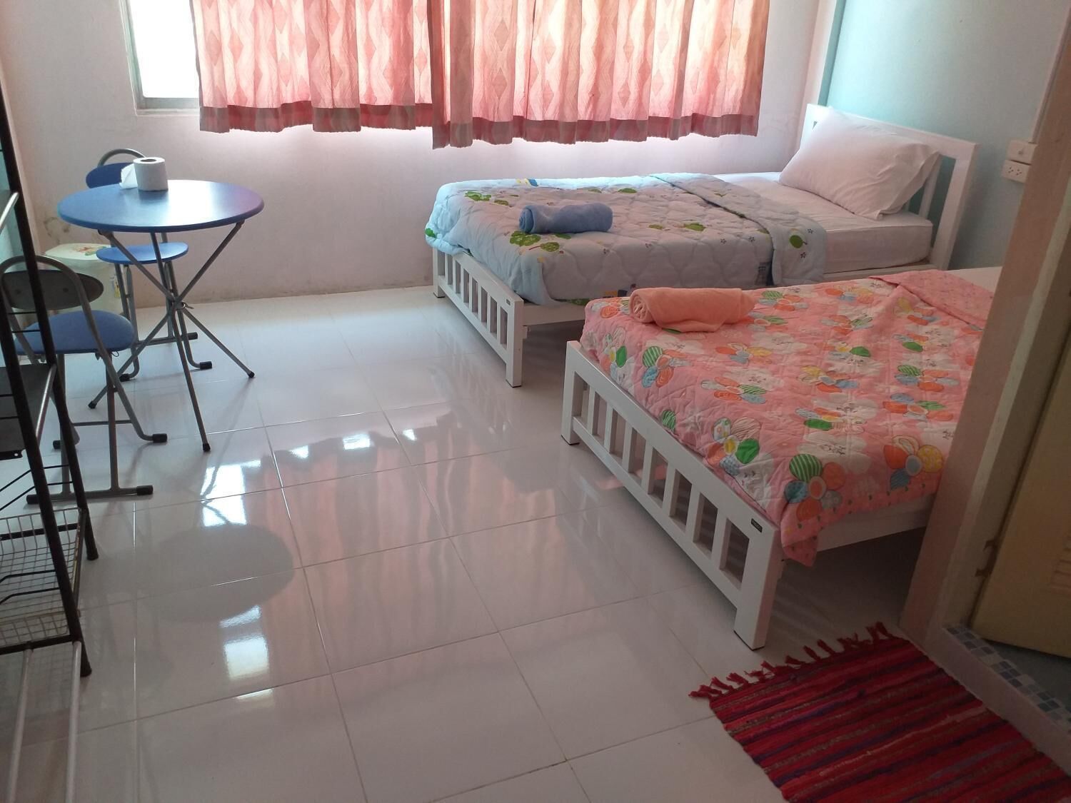 Une chambre avec deux lits, une petite table et une chaise.