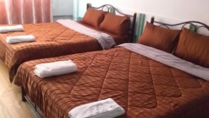 Two twin beds with brown quilts and white towels, metal headboards, and a wooden floor. - OK Home Hostel (Bangkok)