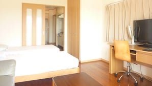 A hotel room with a bed, a desk with a computer, a chair, and a TV. - Ocean Front Miyakojima (Miyakojima)