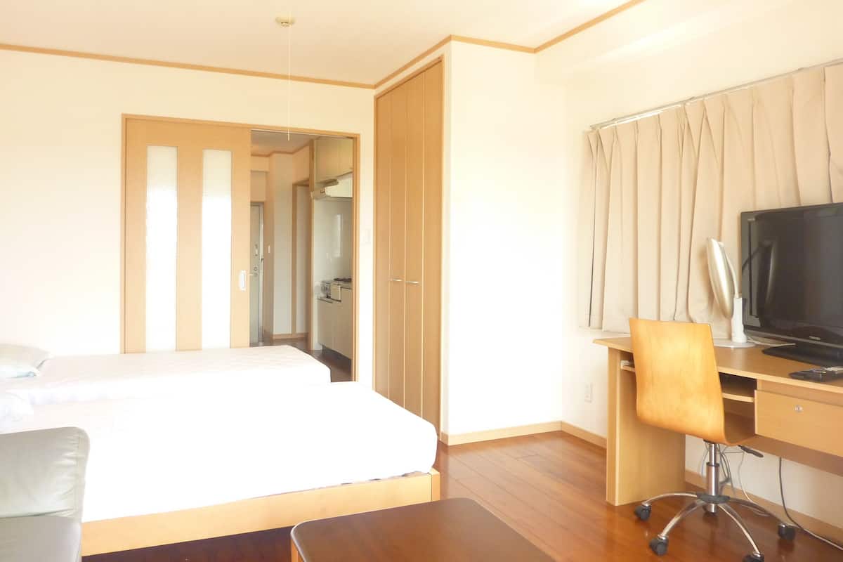 Une chambre d’hôtel avec un lit, un bureau avec un ordinateur, une chaise et un téléviseur.