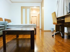 Quarto com cama, escrivaninha, cadeira e sofá.