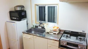 A compact kitchen with a refrigerator, microwave, sink, and stove. - Ocean Front Miyakojima (Miyakojima)