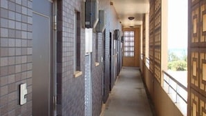 A corridor with tiled walls, doors, and a view through a window. - Ocean Front Miyakojima (Miyakojima)