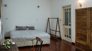 A bedroom with a bed, a wooden wardrobe, a chair, a small table with a vase, and a wooden swing set. - FnF HOUSING (Hanoi)