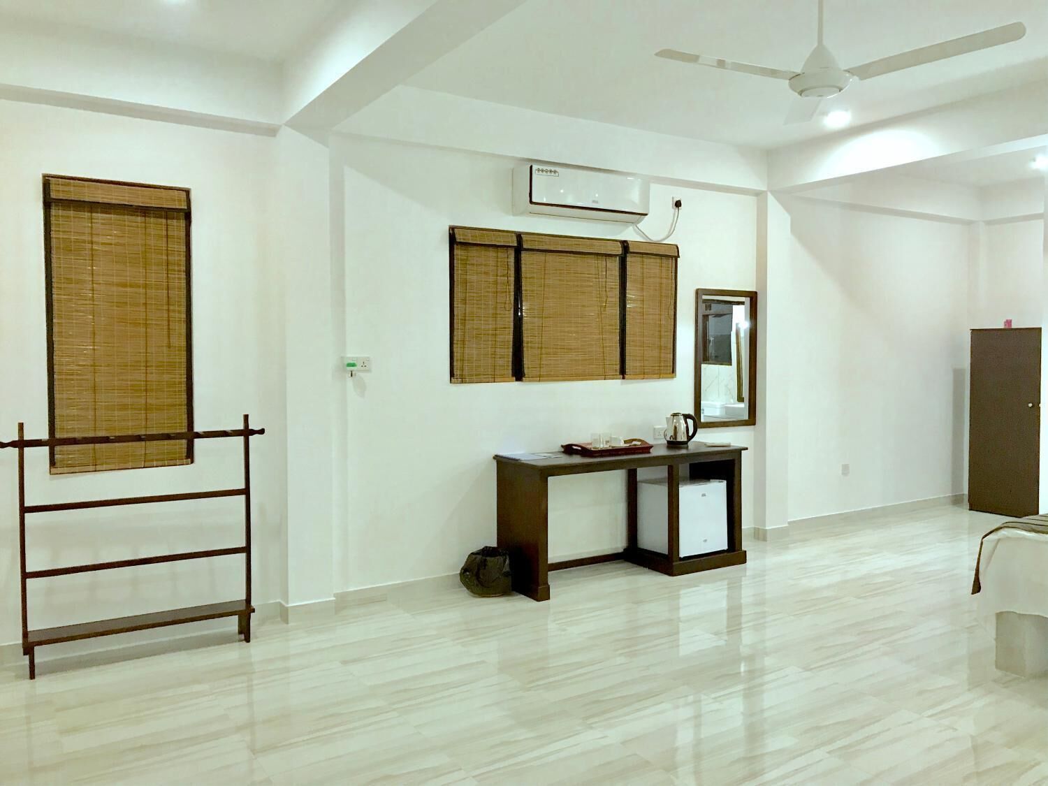 A clean, modern room with a wooden desk, a small cabinet, and a wardrobe.