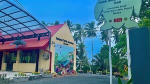 A building with a red roof and a mural of a turtle. There is a sign in front of the building that reads "Community Based Turtle Conservation Project Rekawa". - Ashansa Lagoon Resort (Rekawa)