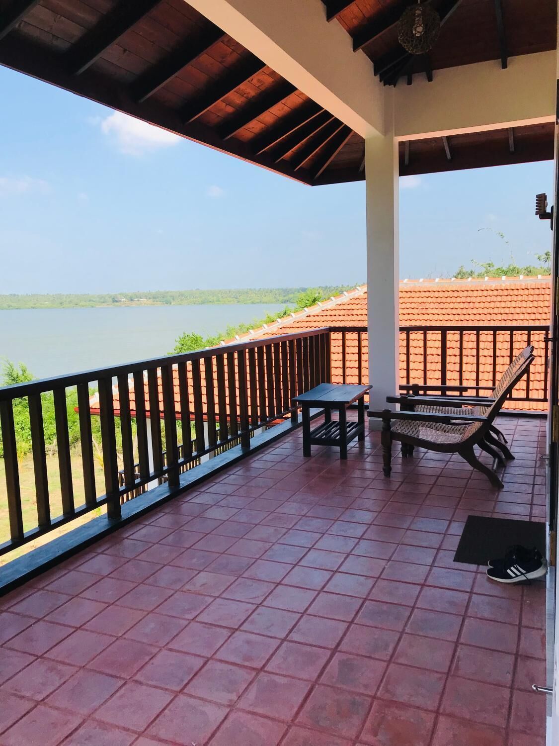 A covered outdoor area with a view of a lake, a table, and two chairs.