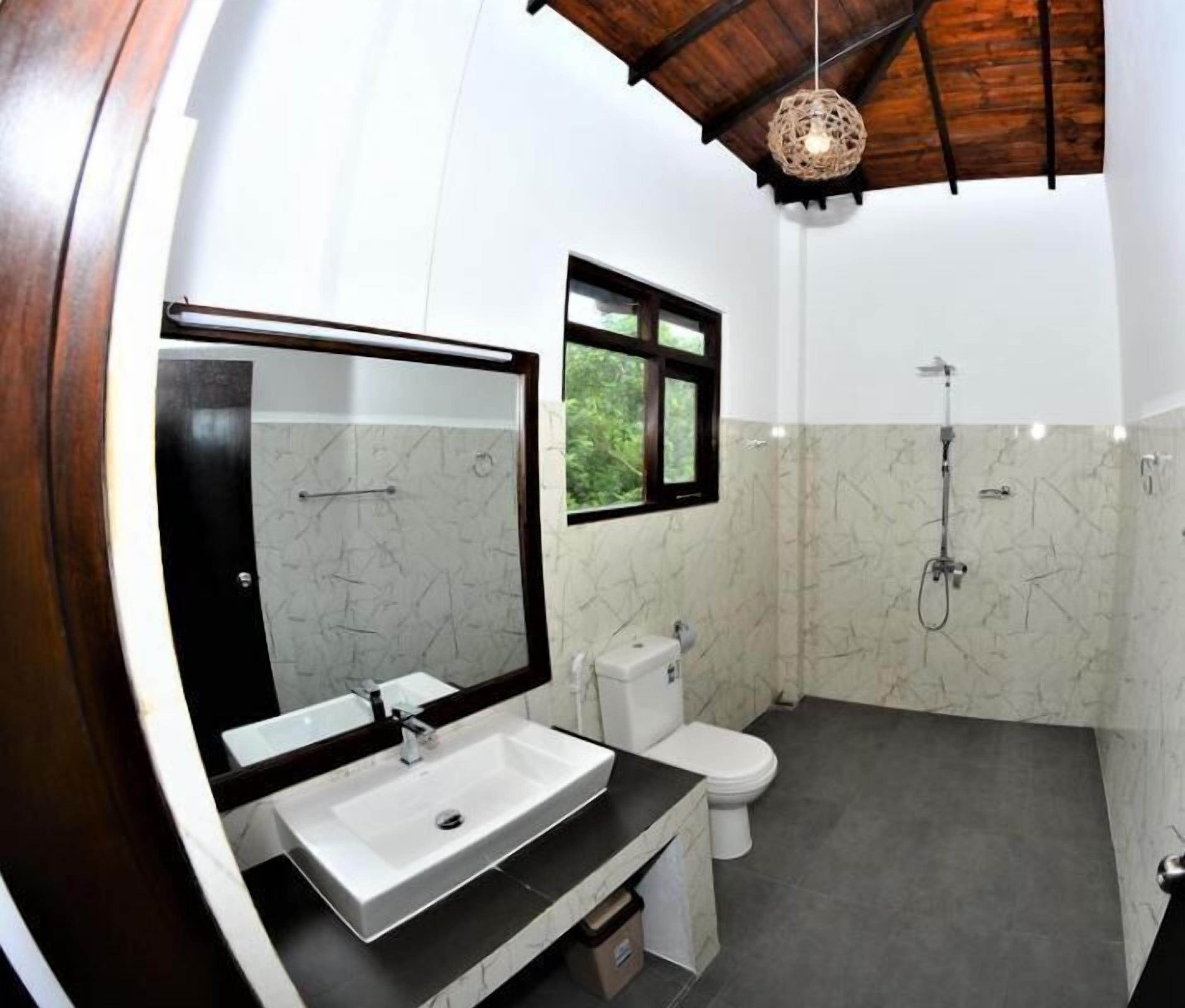 A modern bathroom with a white sink, a large mirror, a toilet, and a shower.