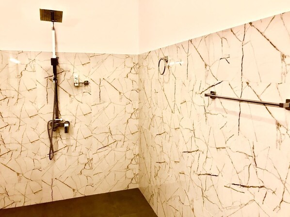 Un baño con pared de mármol, ducha y toallero.