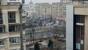 A view of a cityscape with multi-story buildings, a parking lot, and a bank with a visible sign. - Apartment "Life Old Town" (Bucharest)