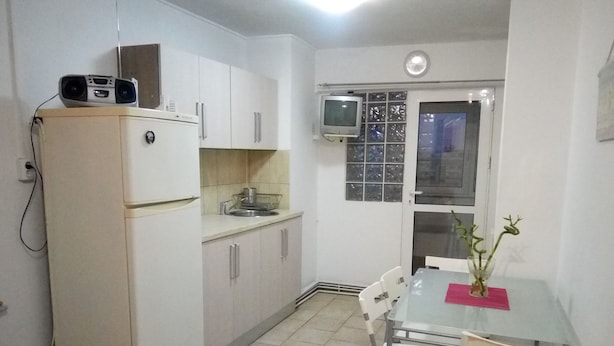 A compact kitchen with white cabinets, a small refrigerator, a microwave, and a television mounted on the wall. - Apartment "Life Old Town" (Bucharest)