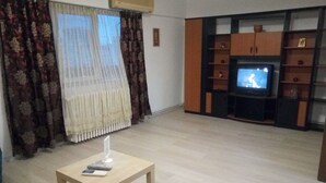 A living room with a television, wooden shelves, and a small table with a remote control. - Apartment "Life Old Town" (Bucharest)