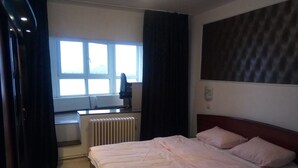 A hotel room with a bed, a desk, a radiator, and a window with curtains. - Apartment "Life Old Town" (Bucharest)