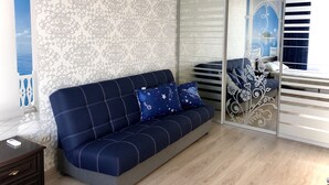A room with a blue sofa, patterned wallpaper, and a sliding glass door with decorative metalwork. - Apartment Yuri 42-76 (Odesa)