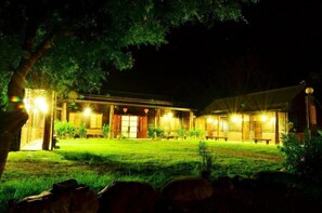 A traditional building with a covered patio area, wooden benches, and a well-lit entrance.