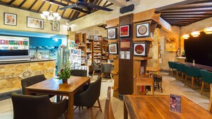 Un restaurante con mesas y sillas de madera, una zona de bar y diversas imágenes enmarcadas en las paredes.
