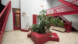 Un intérieur à plusieurs niveaux, avec des rampes rouges et un sol carrelé.