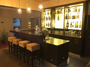 Un espace bar doté d’un long comptoir, de tabourets et d’une variété de bouteilles et de verres.
