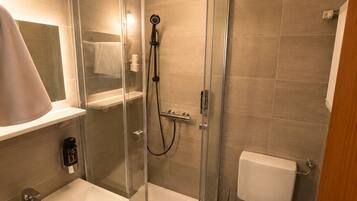 Un baño moderno con ducha de vidrio, lavamanos blanco y un inodoro.