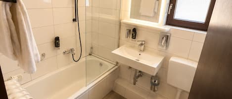 Uma casa de banho moderna com banheira, chuveiro, sanita e lavatório.