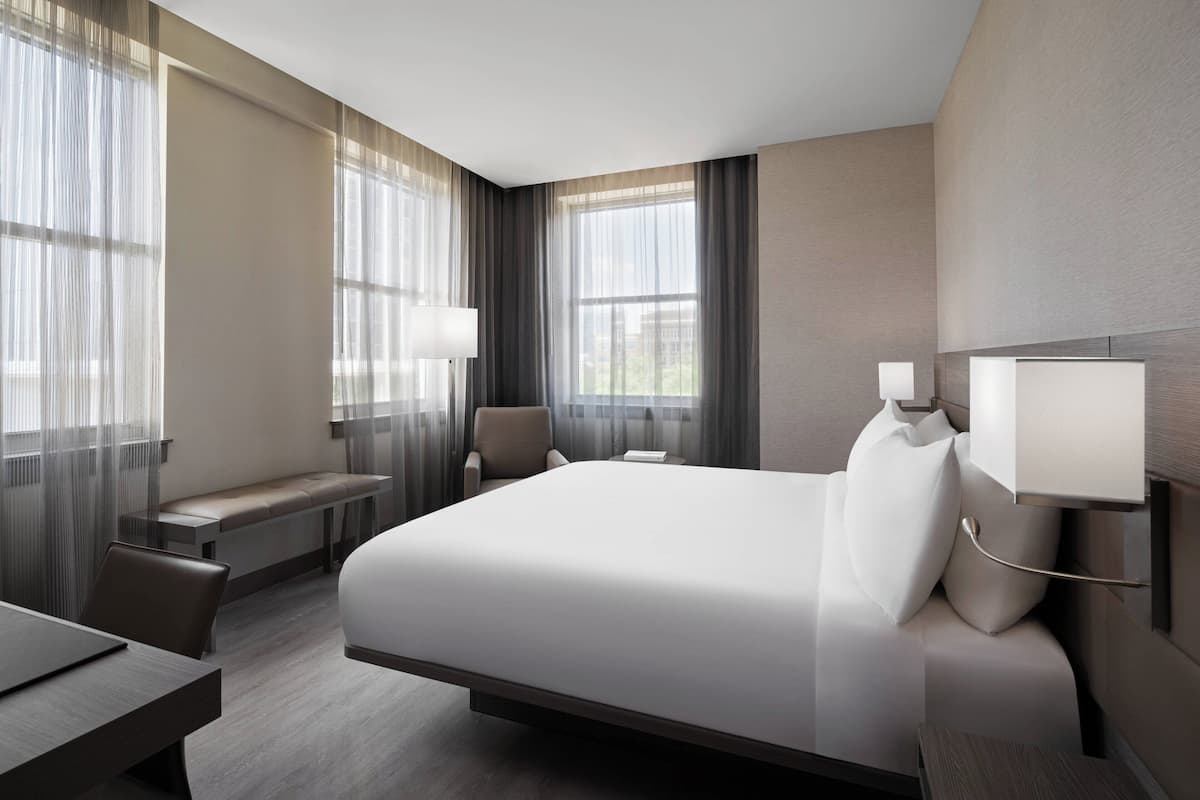 Una habitación de hotel moderna con una cama grande, un escritorio y un banco.