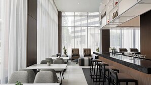 Un restaurante moderno con una barra larga, taburetes y una zona de estar con mesas y sillas.