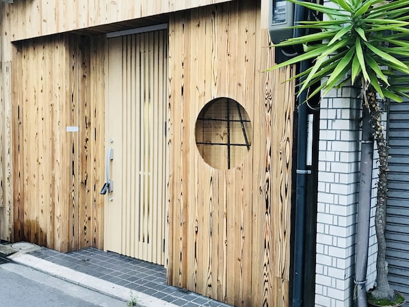 Una puerta de madera con un ventanal circular y un pequeño escalón que lleva a la entrada.