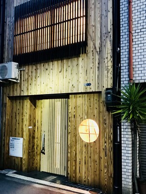 A wooden building facade with a large circular window and a sign indicating a 5-14 age range. - Osaka Premium House (Osaka)