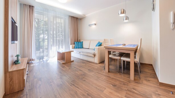 A modern living room with a sofa, a dining table, and a TV.
