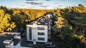 An aerial view of a multi-story building with a flat roof, surrounded by dense forest.