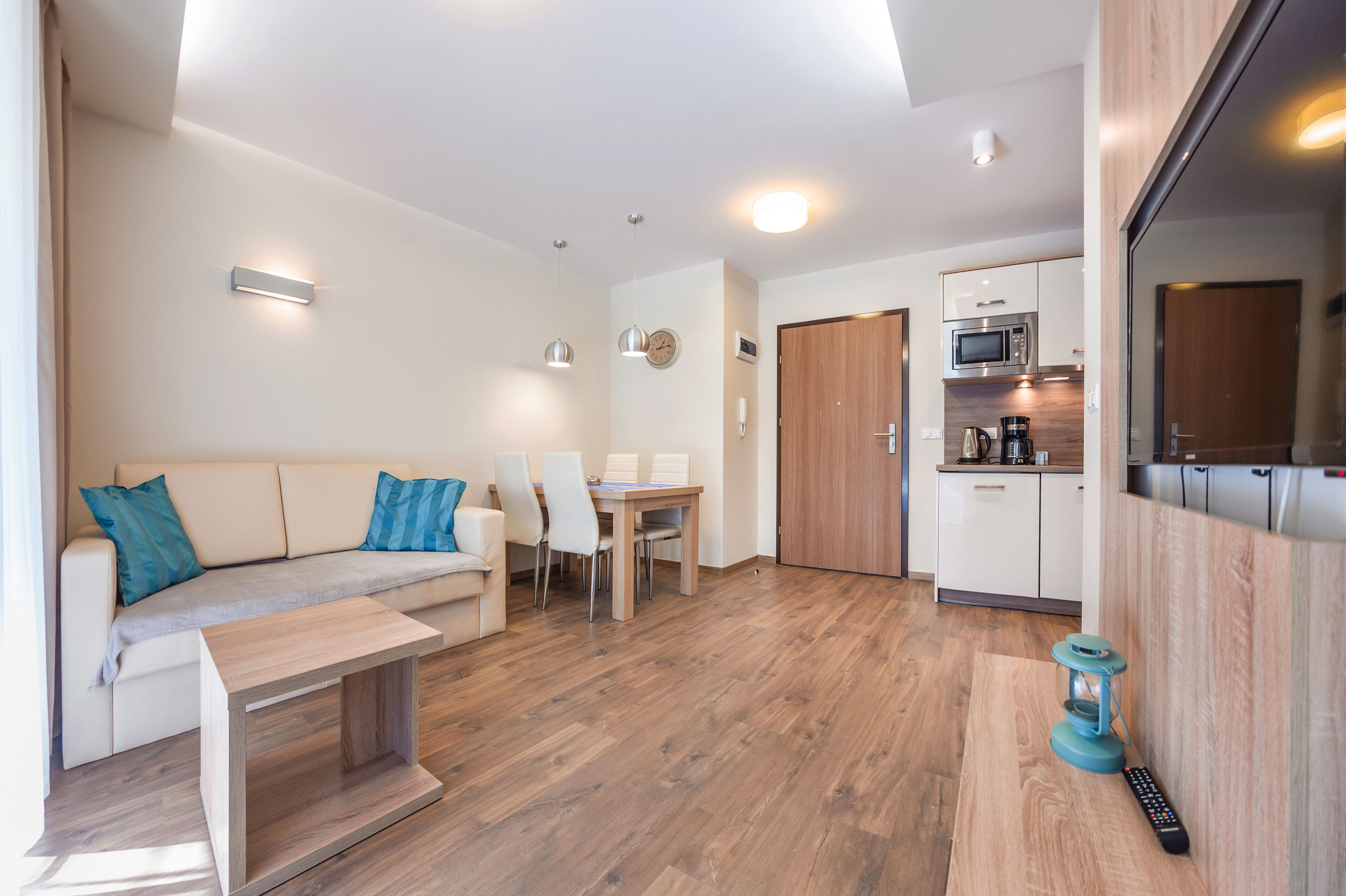 A modern, compact living space with a sofa, dining table, and kitchenette.