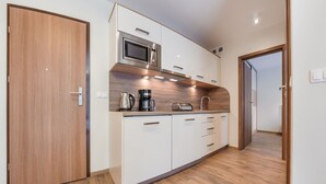 A modern kitchen with white cabinets, a stainless steel microwave, a coffee maker, and a toaster.