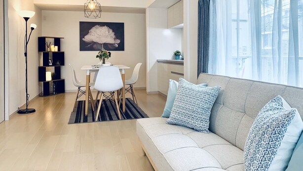 A modern living room with a sofa, a dining table, and a kitchen area. - Shioji Aoi Villa (Osaka)