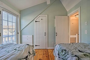 A bedroom with two beds, a white wardrobe, and a bathroom visible through an open door.
