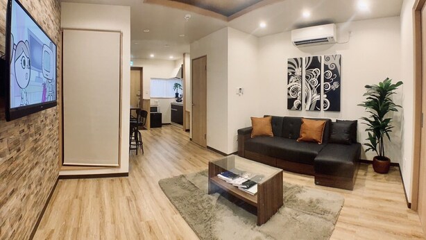 A modern living room with a sofa, coffee table, and artwork on the wall. - Asahi Kasumi Villa (Osaka)