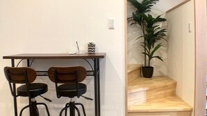 A modern kitchen with a wooden table and two chairs, a potted plant, and a staircase leading to another room. - Asahi Kasumi Villa (Osaka)