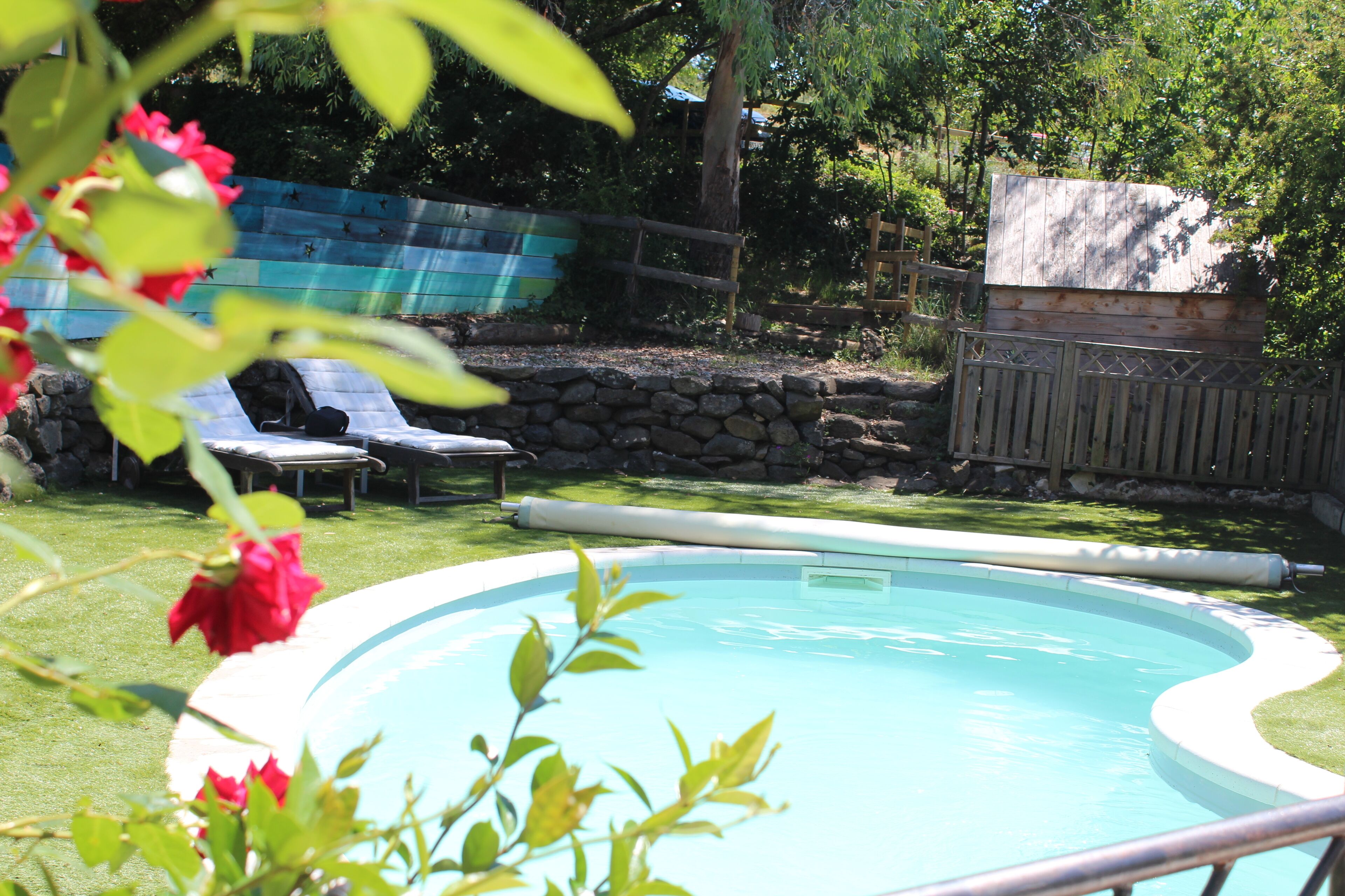 Une piscine avec un mur en pierre et une clôture en bois en arrière-plan.