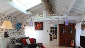 Una sala de estar acogedora con un sofá, una lámpara, una guitarra y una puerta que da a un espacio de almacenamiento.