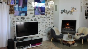 Una sala de estar con un televisor de pantalla plana grande, una chimenea y dos sillones.