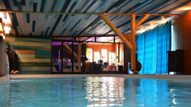 Una piscina interior con vistas a una sala con instrumentos musicales y un escenario.