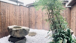 A garden with a wooden fence, a rock formation, and a bamboo plant. - Hanazonominami Apartment 101 (Osaka)
