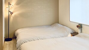 A bedroom with two beds, a floor lamp, and a hanging light fixture. - Hanazonominami Apartment 101 (Osaka)