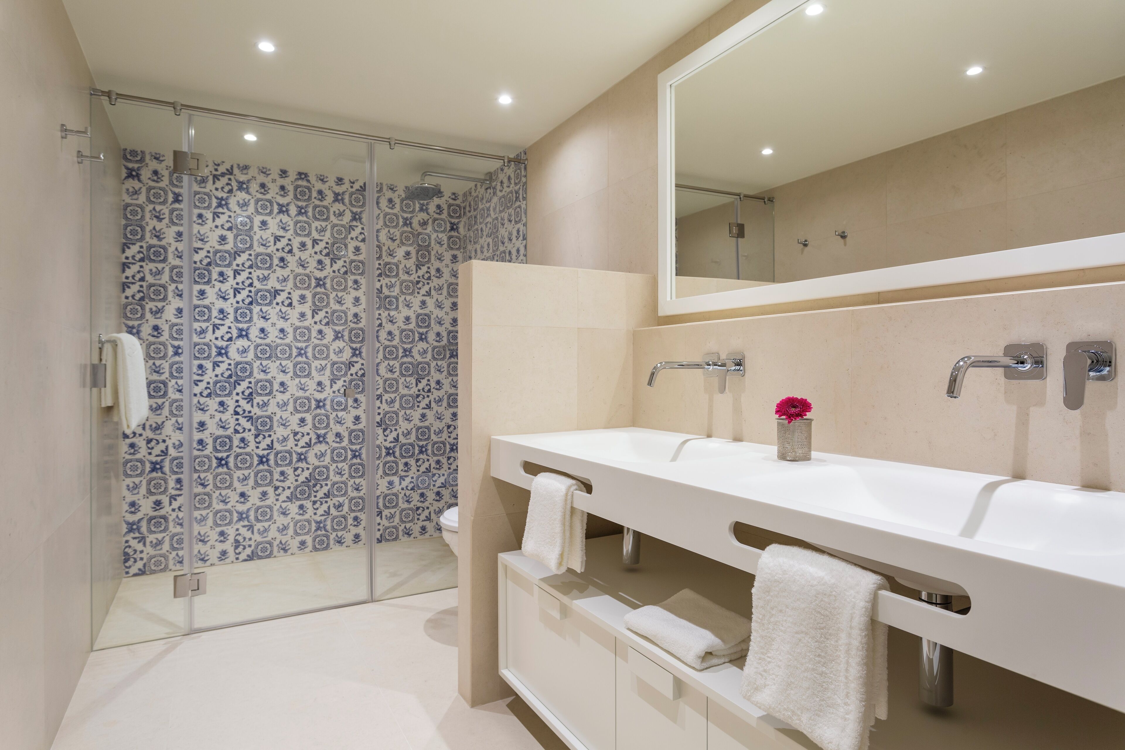 A modern bathroom with a glass shower enclosure, a white vanity with dual sinks, and a large mirror.