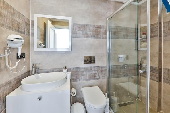A modern bathroom with a large sink, toilet, and glass-enclosed shower. - Carpediem Apart (Kaş)